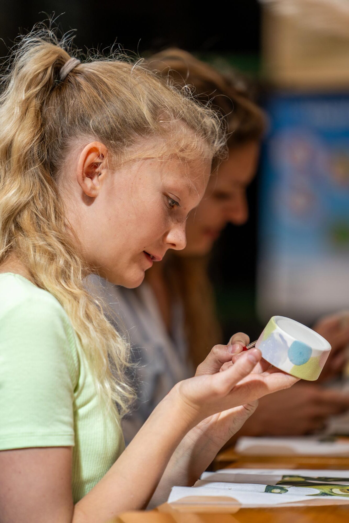 Ein Mädchen bemalt mit dem Pinsel eine Keramikschale.