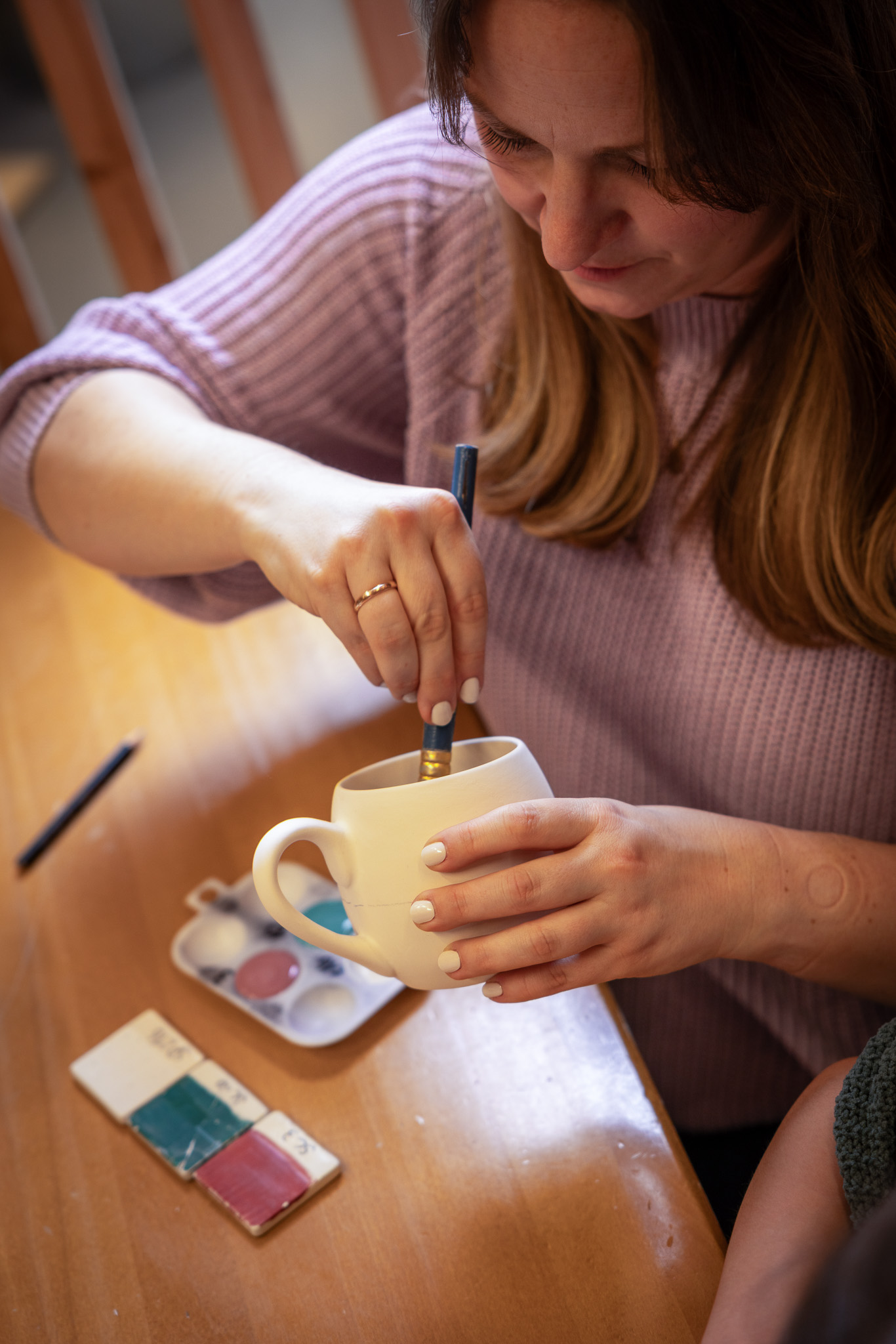 eine Frau bemalt eine Tasse